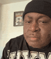 a man wearing a black beanie and a black shirt with the letters t.r.v. on it