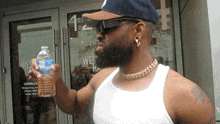 a man holding a bottle of water in front of a building that has the number 1 on it