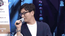 a man wearing glasses and a watch is holding a microphone in his mouth