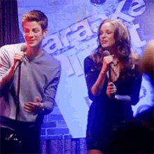 a man is holding a microphone next to a woman who is singing into another microphone .