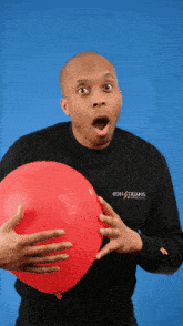 a man holding a red balloon wearing a black shirt that says bdh / trsans