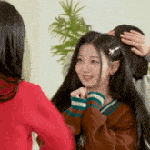 a woman in a brown sweater has a flower in her hair and is smiling