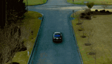 a car is driving down a road with grass on the side