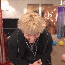 a man with blonde hair is wearing headphones and a necklace with the number 14 on the bottom