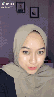 a woman wearing a hijab has a tiktok watermark on her face