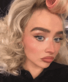 a close up of a woman 's face with blonde hair and a black shirt