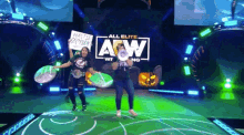 a couple of women holding signs in front of a sign that says all elite wrestling