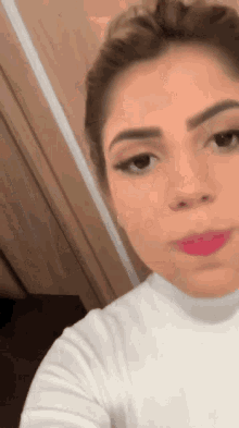 a close up of a woman 's face wearing a white shirt