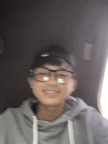 a young man wearing glasses and a hat smiles for the camera