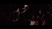 a crowd of people are raising their hands in the air