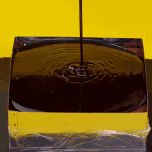 a container of chocolate sauce is being poured into a yellow container