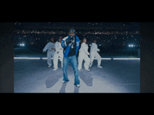 a man in a blue jacket stands in front of a group of dancers