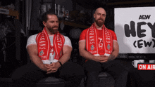 two men are sitting in front of a sign that says hey ( ew )