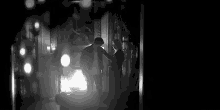 a black and white photo of two people standing next to each other in a living room .