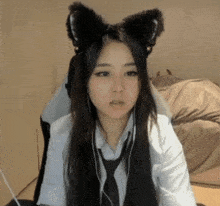 a woman wearing cat ears and a tie is sitting in front of a computer screen .