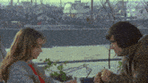 a man and a woman sit at a table with boats in the background and one of the boats says crow fisher