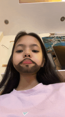 a girl wearing a pink shirt has a beard on her face