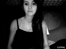 a woman is wearing a black tank top and a necklace .