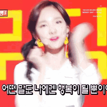 a woman wearing a white shirt and yellow earrings is dancing