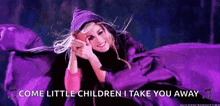 a woman is laying in a purple blanket with the words `` come little children i take you away '' written on it .