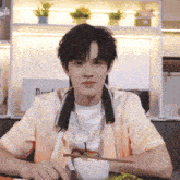 a young man sitting at a table wearing a shirt that says boite