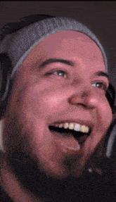 a man wearing a beanie and headphones is laughing with his tongue out