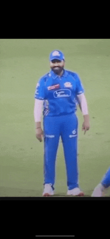 a man wearing a blue shirt and blue pants is standing on a field .