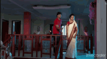a man and a woman are hugging each other and the woman is wearing a red saree .