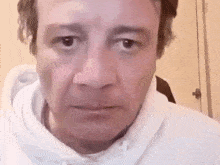 a close up of a man 's face with a white hoodie on .