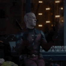 a man in a deadpool costume is clapping his hands in front of a window