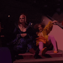 a woman in a yellow and orange dress sits on a staircase