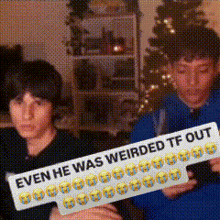 two boys sitting in front of a christmas tree holding a sign that says " even he was weirded tf out "