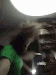 a person in a green shirt is holding a flashlight in a dark room