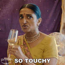 a woman holding a wine glass with the words so touchy behind her
