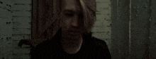 a young man in a dark room with a brick wall