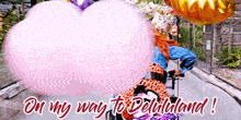 a woman is riding a bike with balloons and cotton candy behind her and the words on my way to delilululand