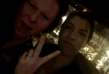 a man and a woman are posing for a picture and the woman is making a peace sign