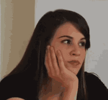 a woman is holding her hand to her face and looking at the camera .