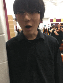 a man wearing glasses and a black shirt stands in front of a group of people playing instruments