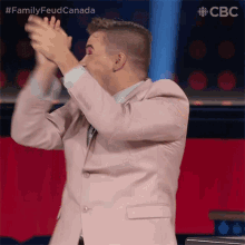a man in a pink suit is applauding with the hashtag familyfeud canada