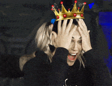 a woman wearing a crown is clapping her hands and smiling