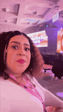 a woman sitting in front of a screen that says " twitch con "