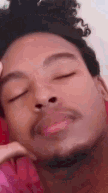 a close up of a man with his eyes closed and his hand on his face .