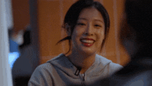 a woman wearing a grey nike hoodie smiles while looking at a man