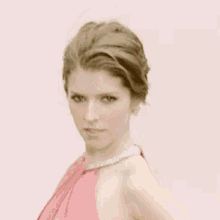 a woman in a pink dress with a pearl necklace