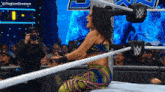 a woman is kneeling in a wrestling ring while a cameraman takes a picture of her