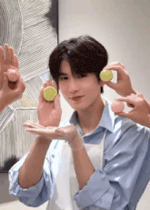 a man in a blue shirt and white apron is holding a lemon in his hand