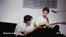 two men are playing guitars in front of a microphone and the word metawin is on the bottom right