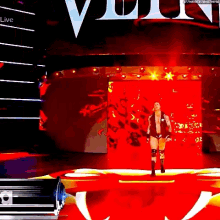 a wrestler is walking down a red carpet on a stage in front of a large screen .