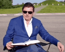 a man in a blue suit and sunglasses is reading a book